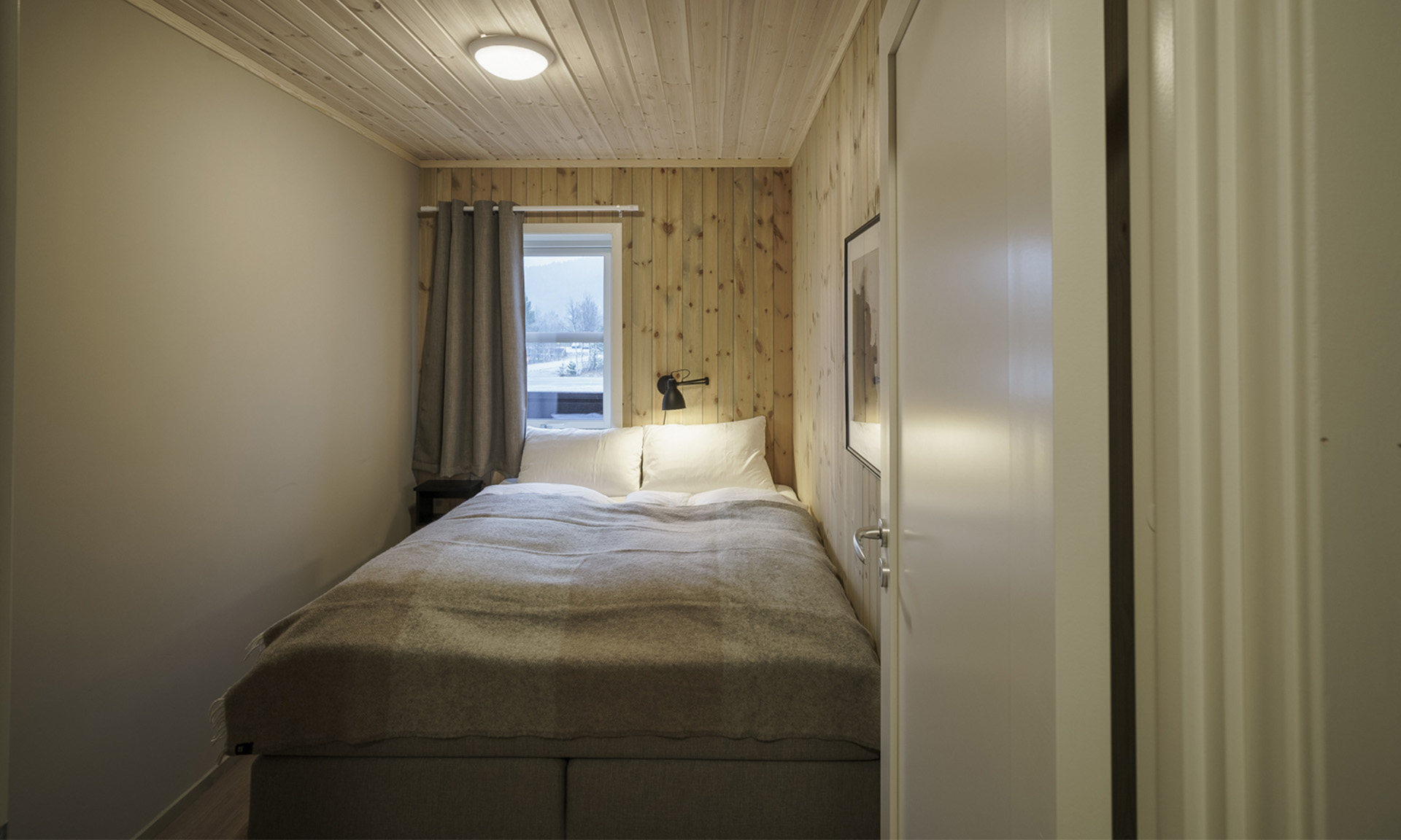 Enkeltrom med seng og vindu, innredet i lune naturmaterialer.