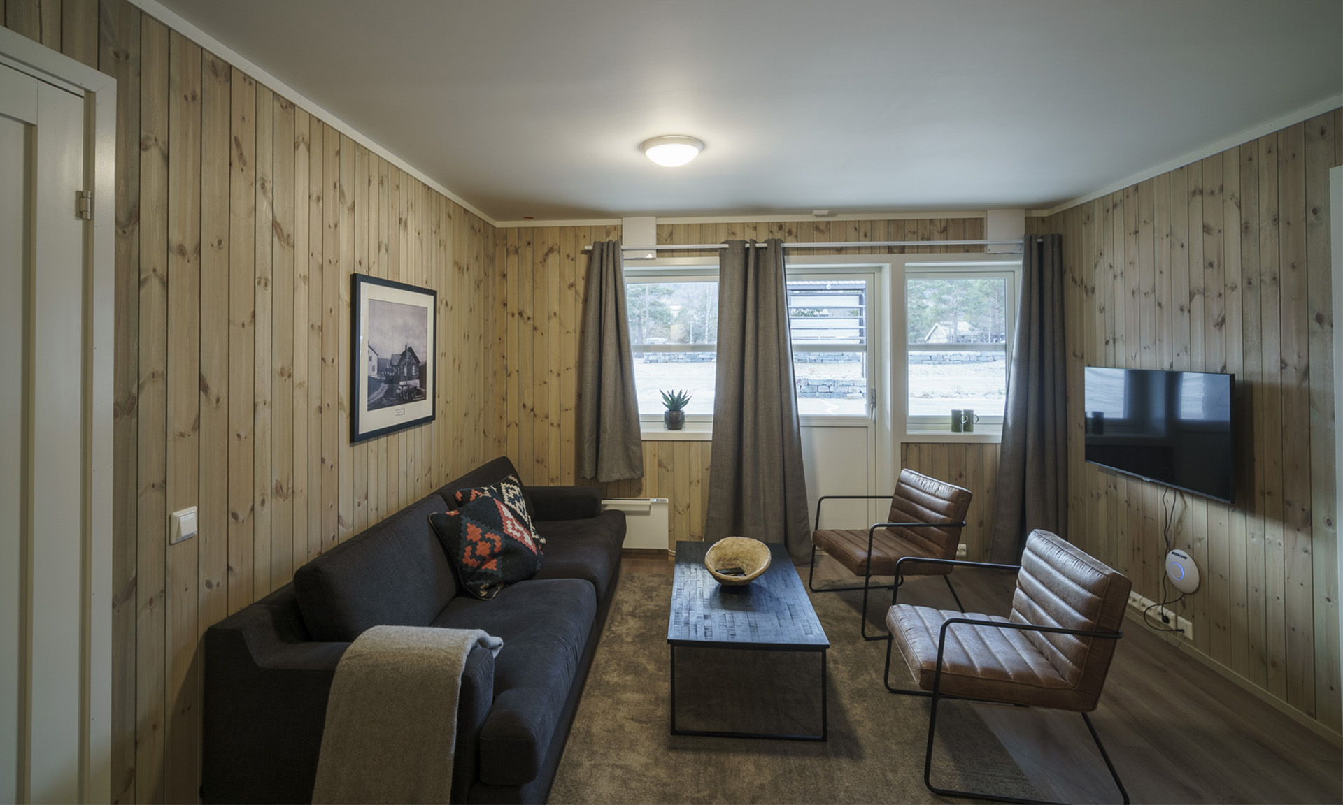 Stue i skandinavisk stil med sofagruppe og TV.